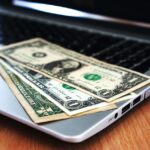 Een ondernemer die zijn zakelijke IBAN nummer onderzoekt op een laptop, met financiële documenten op de tafel.